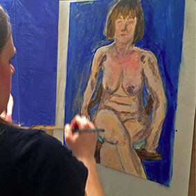Sian painting a figure with blue background on a weekend life class at art courses Wales